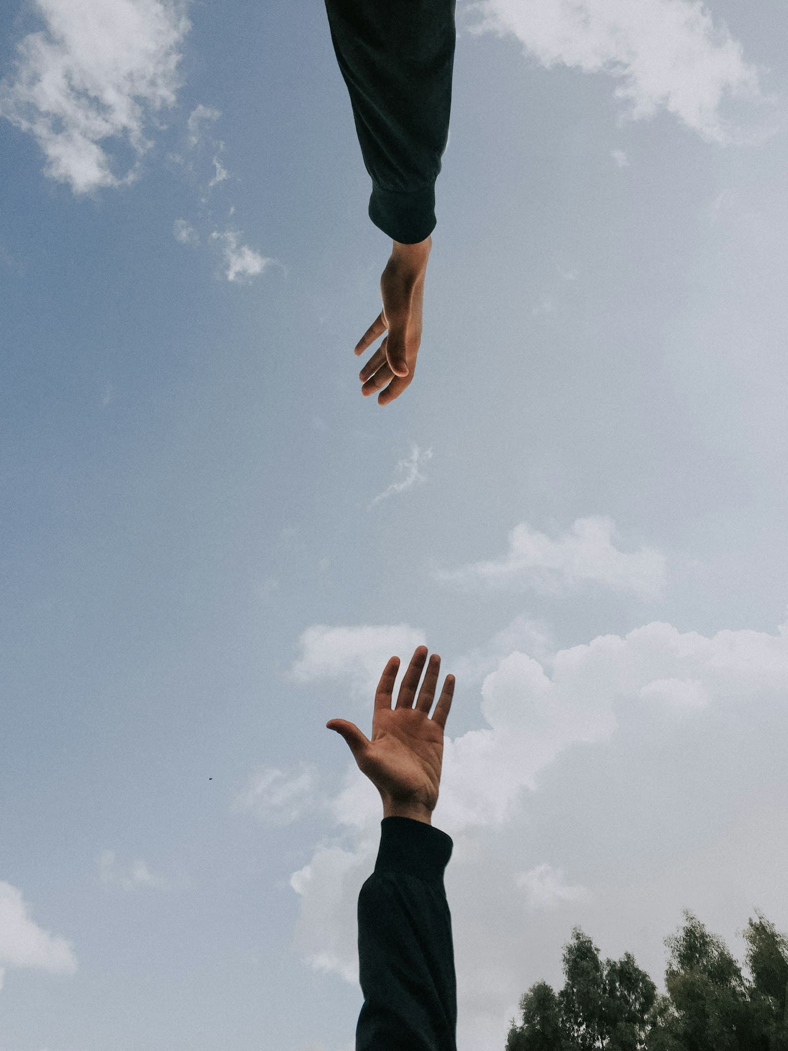 Two hands reaching toward each other against an open sky — a metaphor for therapeutic connection