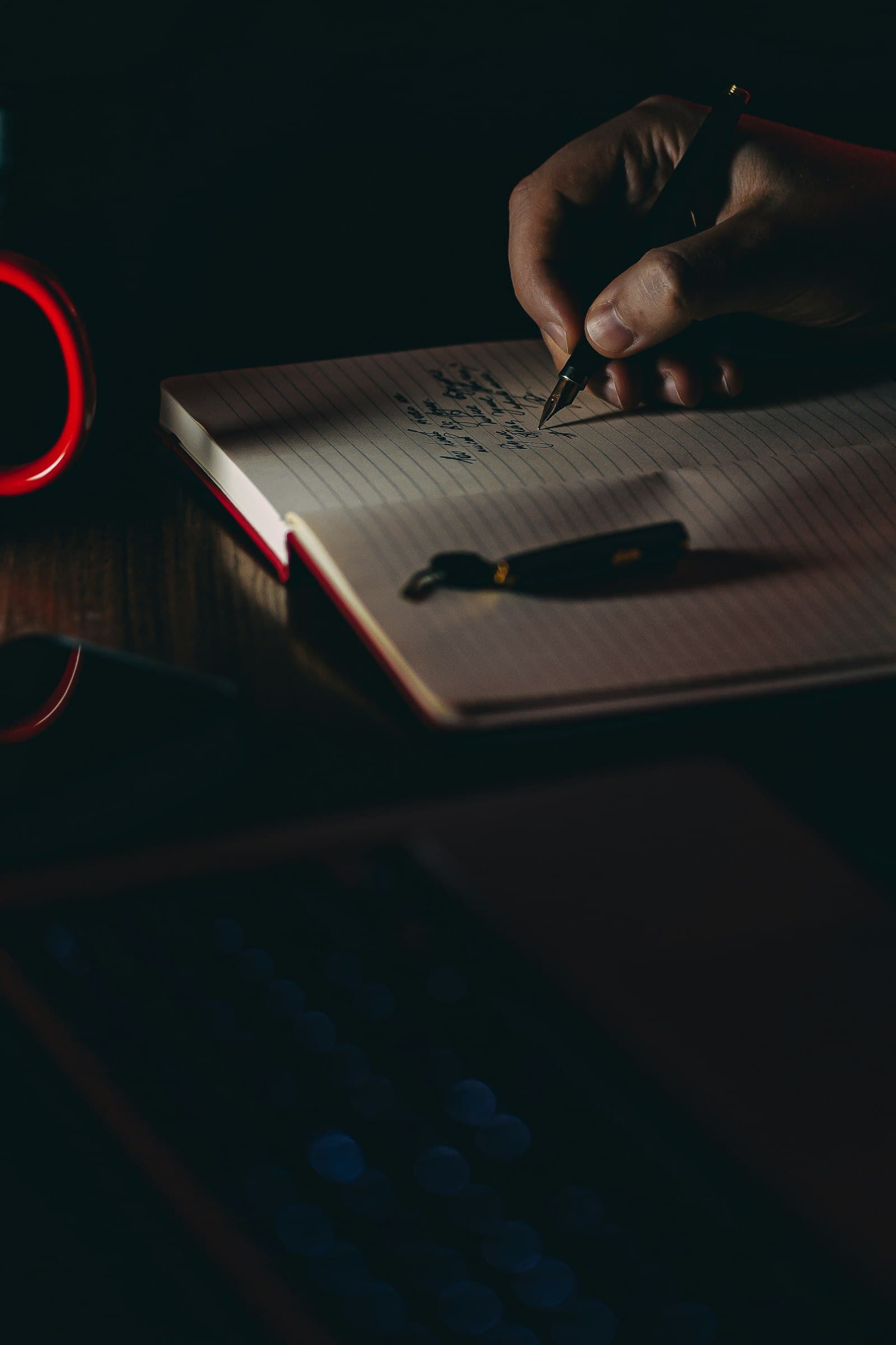 A hand writing with a fountain pen on a notebook under low warm light — precise clinical work
